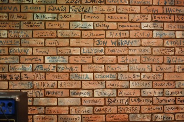 The back wall is made up of bricks, signed by those who have taken stage at B Flat.